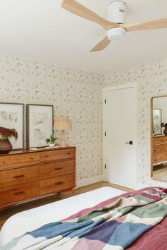 a bedroom with a bed, dresser and ceiling fan in it's center area