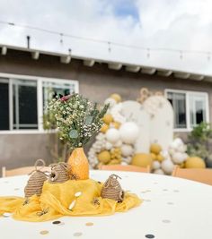 the table is set with yellow napkins and flowers in an orange vase on it