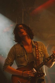 a man with long hair playing an electric guitar