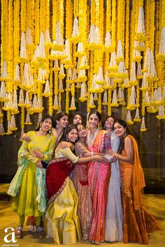 a group of women standing next to each other in front of a chandelier