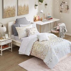 a bedroom with white and gold bedding, pink rugs and pictures on the wall