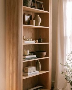 a wooden book shelf filled with books and vases