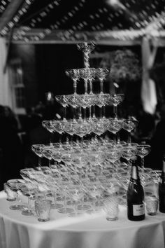 a table topped with lots of wine glasses next to a bottle and glass vases