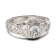 a diamond ring with filigrees and leaves on the sides, set in white gold