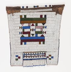 an embroidered wall hanging with geometric designs and fringes on the bottom, in white background