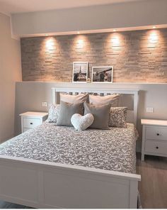 a white bed with pillows and two pictures on the wall above it's headboard