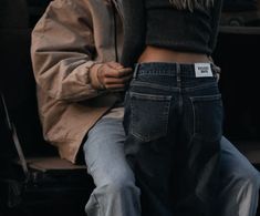 a person sitting on a bench with their back to the camera, wearing jeans and a jacket