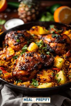 chicken and pineapple rice in a skillet on a table with oranges, lemons and parsley