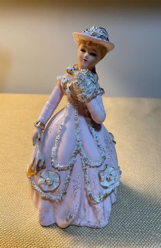 a porcelain figurine wearing a pink dress and hat