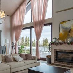 a living room filled with furniture and a fire place in front of two large windows