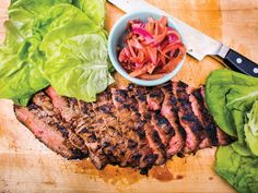 steak, lettuce and red cabbage on a cutting board with a knife next to it