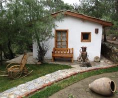 a small white house sitting in the middle of a yard next to a wooden bench