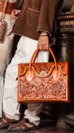 Expertly crafted by skilled artisans, the ALLE "ROMMY" is a stunning masterpiece! This hand-tooled leather weekender and Duffel bag showcases traditional techniques and high-quality cowhide. Versatile and stylish, it's the perfect companion for weekend getaways or as a carry-on for longer travels. The unique tooling adds a touch of sophistication, while the spacious design allows for easy organization and access to your essentials. Made from Full-grain leather, each bag varies in shading due to Luxury Hand Tooled Satchel For Daily Use, Luxury Hand-tooled Leather Satchel, Luxury Hand Tooled Leather Satchel, Artisan Leather Bag With Engraving, Luxury Hand-tooled Satchel For Travel, Luxury Hand Tooled Satchel For Travel, Luxury Hand-tooled Travel Satchel, Artisan Engraved Rectangular Bag, Artisan Rectangular Engraved Bag