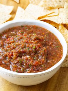 a white bowl filled with salsa and tortilla chips on top of a wooden table