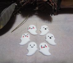 five white ghost buttons sitting on top of a table next to a potted plant