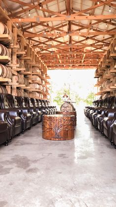 a room filled with lots of brown leather chairs and barrels stacked on the wall next to each other