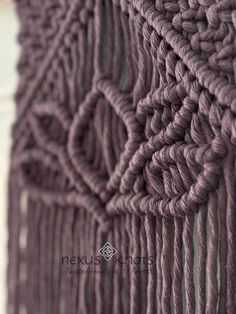 a close up view of a purple crocheted wall hanging