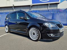 a black car parked in front of a blue fence