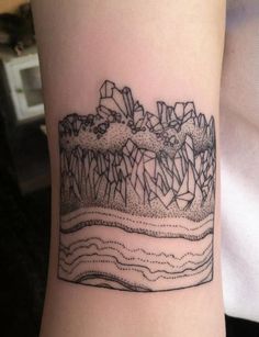 a black and white tattoo on the arm of a person with mountains in the background