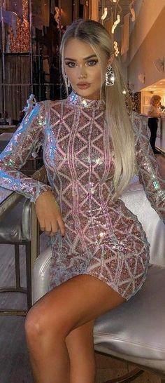 a woman sitting on top of a white chair wearing a dress with sequins