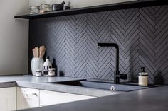 a kitchen with black and white herringbone tile on the backsplash is shown