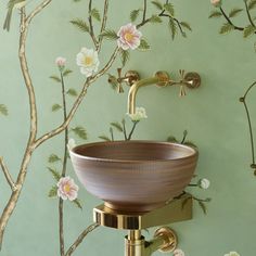 a bathroom sink sitting under a faucet next to a wall with flowers on it