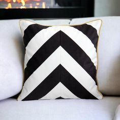 a black and white pillow sitting on top of a couch next to a fire place