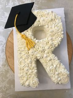 a cake shaped like the letter r with a graduation cap on top and flowers around it