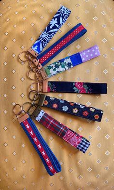 six pairs of keychains with different patterns on them sitting on a yellow surface