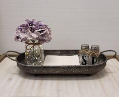 a metal tray with flowers and salt and pepper shakers on it, sitting on a table