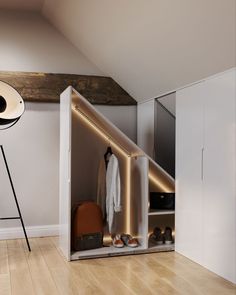 an open closet with clothes and shoes on the floor next to a tripod light