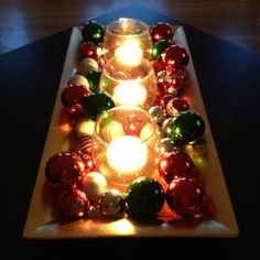 lighted candles are arranged in the shape of a christmas tree on a long tray with ornaments