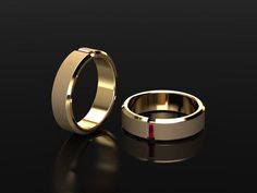 two gold wedding bands with one red stone in the middle on a black background photo