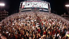 a large group of people standing in front of a stadium