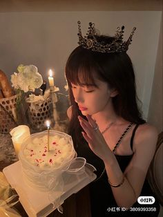 a woman wearing a tiara blowing out candles on a cake