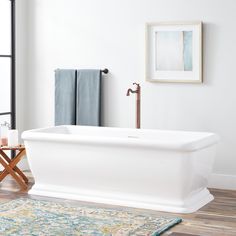 a white bath tub sitting on top of a hard wood floor next to a rug