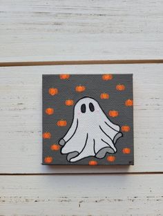 a painting of a ghost with pumpkins around it on a white wooden surface,