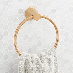 a towel hanging on the wall next to a gold metal holder with a circular handle