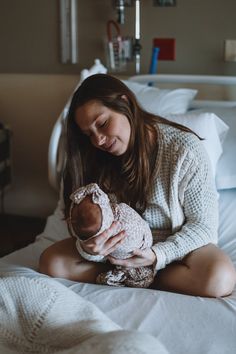 a woman holding a baby on top of a bed