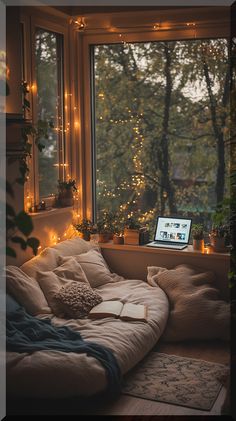 a laptop computer sitting on top of a bed in front of a window covered in fairy lights