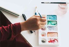 a person is painting with watercolors on a table