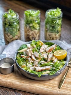 a salad with lettuce, chicken and lemon wedges on a cutting board