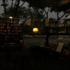 a table with some books on it and a lamp in the window next to it