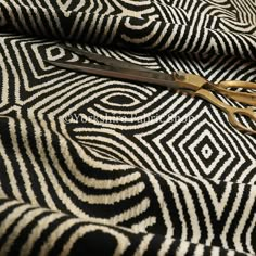 a pair of scissors sitting on top of a black and white cloth with an intricate design