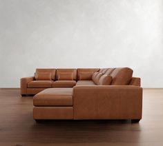 a brown leather couch sitting on top of a wooden floor next to a white wall