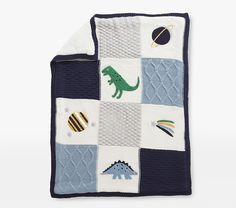 a blue and white blanket with dinosaurs, planets, and other things on the side