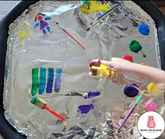 the child is painting on tin foil with colorful paints