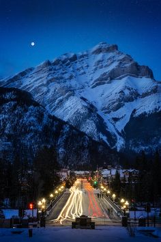 the mountains are covered in snow and lit up by street lights at night with long exposure