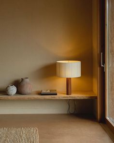 a lamp sitting on top of a wooden shelf next to a window