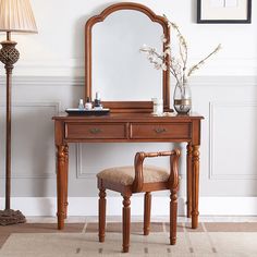 a dressing table with a mirror, stool and lamp